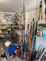 Multiple fishing rods in wooden rack against workshop backdrop