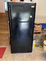 Closed front view of the black refrigerator showing exterior condition