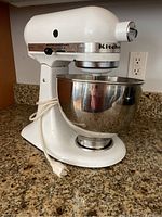 Front-left view showing mixer with attached bowl and power cord coiled at base