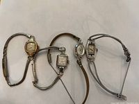 Four ladies wristwatches displayed side by side showing variety of cases and bands