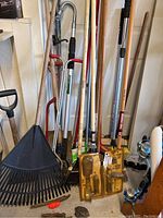 Full view of long-handled tools leaning against wall