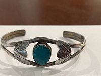 Front view of the sterling silver cuff bracelet showing turquoise centerpiece and silver leaf designs.