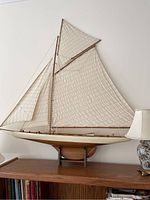 Front view of wooden sailboat model showing hull, deck details, and sails