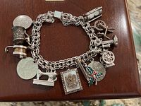 Full view of the sterling silver charm bracelet with multiple charms on a wooden surface.