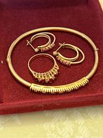 bangle, ring and earrings arranged on red velvet background