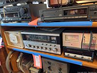 Wide view of shelf showing all four main items: Realistic DX-150B receiver, Alliance azimuth indicator, Heath digital frequency counter, and Polar Electronics signal meter.