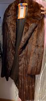 Front view of full-length brown mink fur coat on hanger, showing collar and body