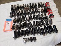 Vacuum tubes laid out on white cloth showing variety of sizes and brands, including RCA.