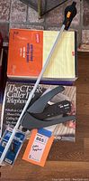 Photo of stapler, legal writing pads, reacher, Caller ID phone, and other office supplies