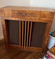 Full front view of the stereo cabinet showing wooden veneer finish with vertical wood slats in front of speaker grille.