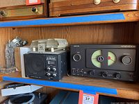 Photo showing wooden shelf holding the Yaesu External Speaker SP-6, Hallicrafters Model S-38 radio receiver, and boxes of parts on the side.