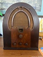 Front view of the vintage Philco wooden radio showing fabric speaker grill, PHILCO branded tuning window, and four control knobs.