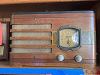 Front view of the vintage Zenith radio showing wood veneer case with horizontal grill, fabric, and tuning dial with two control knobs