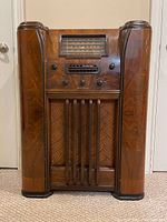 Front view of walnut veneer console radio with vertical speaker grille and control panel