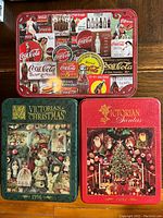 Three collectible puzzle tins: one Coca Cola themed with vintage bottle and logo graphics; two Christmas themed Springbok Special Edition puzzles titled 'Victorian Christmas 1996' and 'Victorian Santas 1995'.