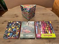Overview of the four Springbok jigsaw puzzles arranged on a table, showing different box designs and the variety of pieces count.