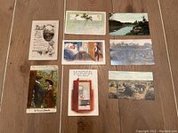 All eight postcards laid out on wood surface, showing front illustrations and scenes
