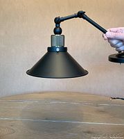 Single assembled sconce held in hand showing shade and arm detail