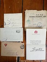 Four WW1 military letters with envelopes and a Buckingham Palace memorial note, displayed on a wooden surface.