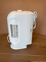 Side view of compact white True Air air purifier, showing vent grill and logo on side.