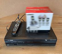 Front and top view of Cisco Nextbox Explorer 8642HD PVR with remote control placed on top and a box next to it.