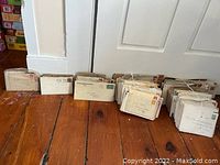 Five piles of vintage stamped envelopes arranged on hardwood floor, showing quantity and grouping by decade from 1900s to 1940s.
