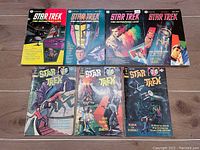 Front view of all 7 Star Trek comics and books showing colorful illustrated covers with titles and prices visible on comics and books.