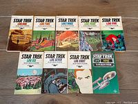 Complete set of nine Star Trek Log paperback books arranged in two rows, showing front cover artwork and titles from Log One to Log Nine.