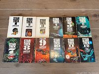 Twelve Star Trek paperback books laid out in two rows, numbered 1 through 12 with various cover art, all adapted by James Blish.