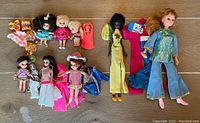 Wide view of all vintage dolls and clothing spread on floor showing variety of dolls and apparel.