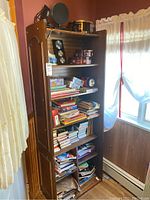 Full image of the wooden shelf filled with books, puzzles, games and miscellaneous items.