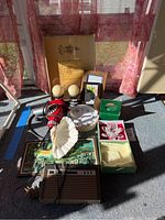 Overview photo of entire lot showing all items arranged on floor near window with sunlight, including heat tool, radio, clock, candles, candle holders, crystal item, shell dish, framed art and small mirror.