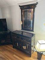 Full view of sidebar with drawers and shelves underneath, showing black painted finish with gold-tone decorative inlays and brass handles.