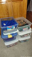 Stacked plastic containers holding various winter scarves, hats, and accessories.