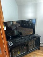 Front view of Samsung 48-inch TV on black cabinet with remote next to it.