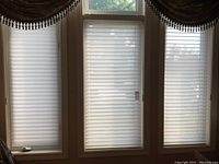 Three white pleated blinds installed in window frames, showing overall condition and coverage.