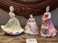 Front view of all three Royal Doulton figurines placed on a shelf showing detailed dresses and poses