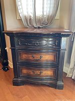 Front view of the chest showing the three drawers with different handles and carved details.
