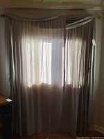 Curtain set on window showing layered grey panels with patterned white liners and draped valance.