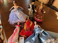 Overview of all six dolls laid out on table showing full outfits and general condition