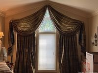 Window with draped grey raw silk curtain panels and a matching valance with heavy fringe.