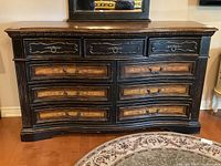 Full front view of black distressed chest with natural wood tone drawer fronts