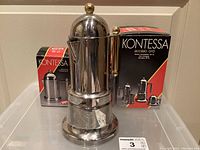 Front view of Kontessa espresso maker and matching cream and sugar sets in original boxes.