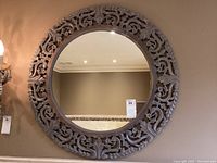 Full front view of the large round carved wooden wall mirror, showing overall pattern and mirror surface.