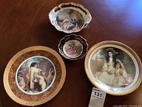Overview of three Limoges plates of various sizes including two large plates with gold trim and two smaller decorative plates, showing the scenic artwork on each.