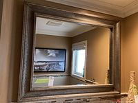 Full front view of mirror reflecting framed picture and window