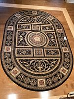 Full view of oval carpet showing overall design and condition on wooden floor.