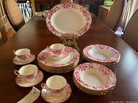Overview of lot: 4 teacups with saucers, stacks of dinner plates, rimmed soup bowls, and oval platter.