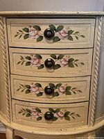 Close-up of four drawers with pink rose hand-painted floral design and metal drawer knobs.