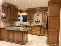 Full kitchen layout with solid wood upper and lower cabinets, island, and space for appliances
